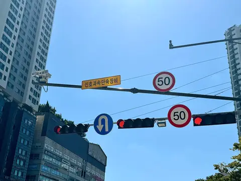 신호 · 과속 단속 카메라와 제한 속도 50 표지판 — 도시 도로에서는 시속 50 km 보다 느리게 달려야 해요